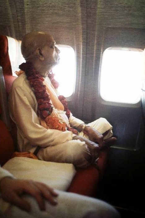 Srila Prabhupada sitting in an airplane